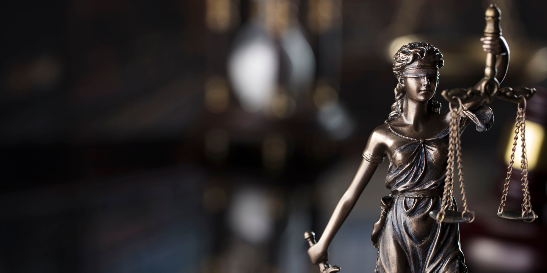 Εικόνα του αγάλματος της τυφλής δικαιοσύνης από μπρούτζο που κρατά μια ζυγαριά στο αριστερό χέρι και ένα σφυρί στο δεξί χέρι σε θολό φόντο